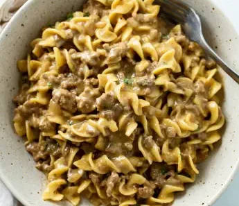 Ingredients: 1 lb ground beef 1 medium onion, chopped 2 cloves garlic, minced 8 oz egg noodles 1 can (10.5 oz) cream of mushroom soup 1 can (10.5 oz) beef broth 1 cup sour cream 1 tablespoon Worcestershire sauce 1 teaspoon dried parsley Salt and pepper to taste 1 tablespoon olive oil Optional: chopped fresh parsley for garnish Instructions: Cook the Egg Noodles: Bring a large pot of salted water to a boil. Add the egg noodles and cook according to the package instructions until al dente. Drain and set aside. Cook the Beef: In a large skillet, heat the olive oil over medium heat. Add the chopped onion and cook until softened, about 3-4 minutes. Add the ground beef to the skillet. Cook, breaking it up with a spoon, until browned and no longer pink. Drain any excess fat. Add the minced garlic to the beef and cook for another minute until fragrant. Prepare the Sauce: Stir in the cream of mushroom soup, beef broth, Worcestershire sauce, dried parsley, salt, and pepper. Mix well to combine. Bring the mixture to a simmer and cook for 5-7 minutes, allowing the flavors to meld together. Combine Noodles and Sauce: Reduce the heat to low and stir in the cooked egg noodles until well coated with the sauce. Add the sour cream and gently mix until the sauce is creamy and the noodles are well coated. Serve: Taste and adjust the seasoning with more salt and pepper if needed. Serve hot, garnished with chopped fresh parsley if desired. This Easy Beef and Noodles recipe is perfect for a quick and comforting meal. Enjoy!